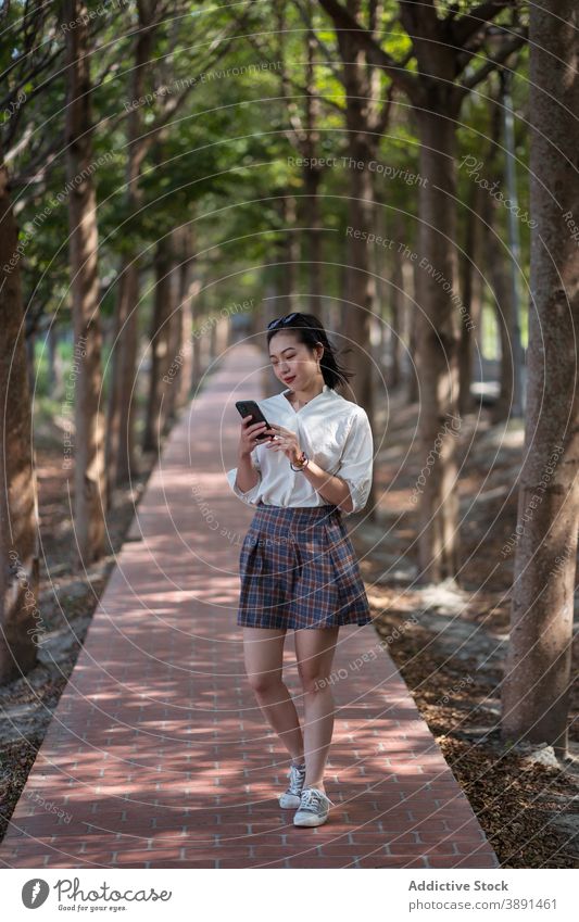 Asiatische Frau surft Handy im Park Smartphone Browsen Sommer sich[Akk] entspannen unterhalten Textnachricht soziale Netzwerke Gasse ethnisch asiatisch