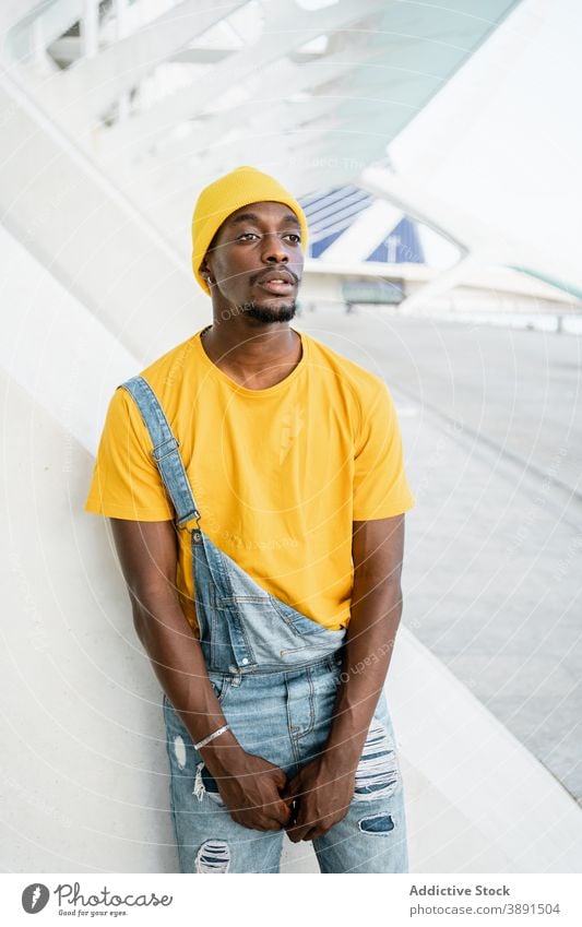 Schwarzer Mann steht auf der Straße und schaut in die Kamera trendy männlich ethnisch schwarz Afroamerikaner gelb Outfit Stil modern hell Vorschein