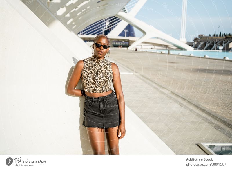 Ernste schwarze Frau steht auf der Straße ethnisch Afroamerikaner cool Sonnenbrille Stil urban jung trendy expressiv Kleidungsstück hell Individualität Geflecht