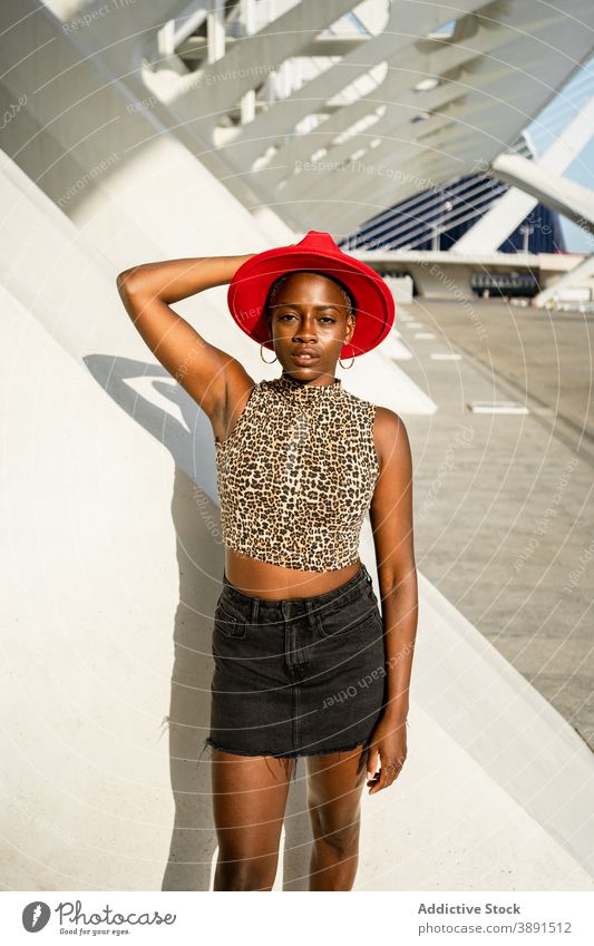 Stilvolle schwarze Frau mit rotem Hut in der Stadt Großstadt verträumt sorgenfrei urban trendy Accessoire ethnisch Afroamerikaner in die Kamera schauen sonnig