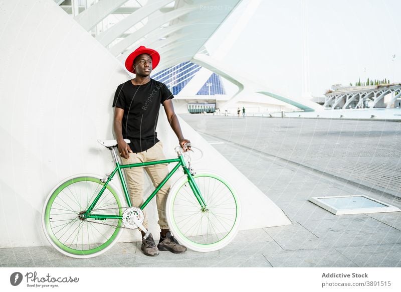 Stilvoller schwarzer Mann mit Fahrrad in der Stadt urban Großstadt jung modern trendy selbstbewusst männlich ethnisch Afroamerikaner Straße Vorschein Hipster
