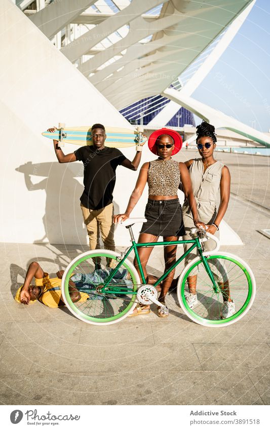 Gesellschaft von fröhlichen Freunden mit Fahrrad und Longboard in der Stadt Unternehmen Hipster Einheit cool Stil Generation Zusammensein ethnisch schwarz