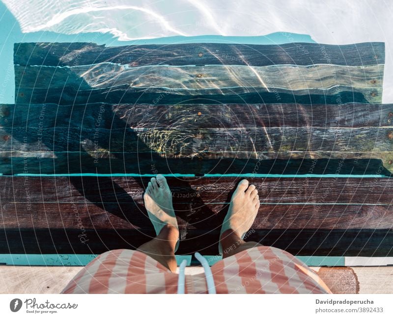Unbekannter Mann ruht am Pool Beckenrand Bein Sommer Urlaub hölzern Resort Rippeln ruhen reisen Wasser sich[Akk] entspannen Sauberkeit Barfuß Tourist Feiertag