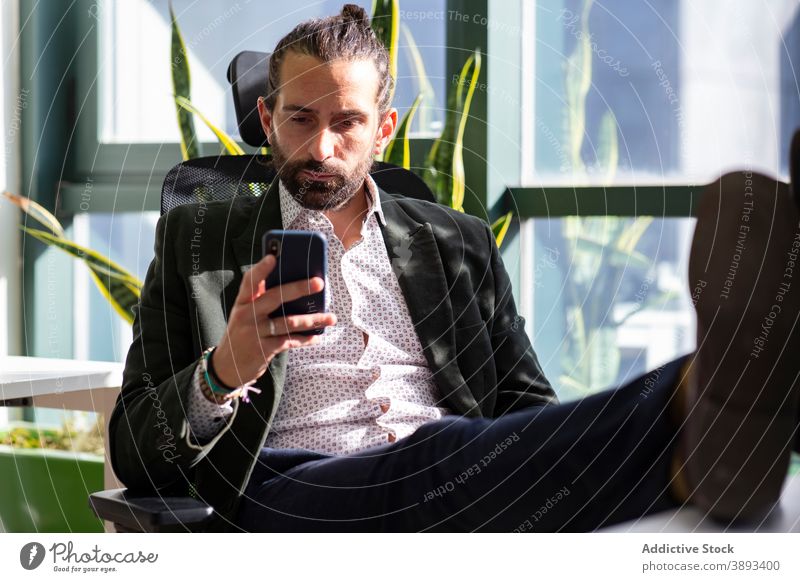 Seriöser Geschäftsmann nutzt Smartphone im Büro benutzend lesen Konzentration ernst Unternehmer Telefon Mobile Pause Mann Vollbart formal Arbeit Arbeitsbereich