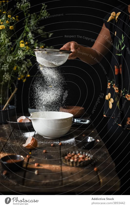 Frau siebt Mehl in Schüssel Sieb Gebäck vorbereiten Bestandteil Lebensmittel hinzufügen Küche kulinarisch Teigwaren Koch Prozess selbstgemacht Dessert Mahlzeit