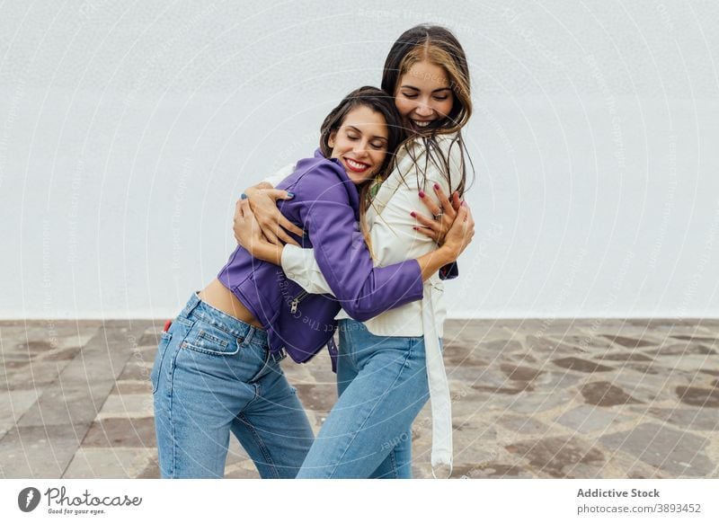 Glückliche Freundinnen umarmen auf der Straße Umarmen trendy jung heiter Sitzung urban Zusammensein Lachen Frau Freundschaft Partnerschaft Freude Frauen froh