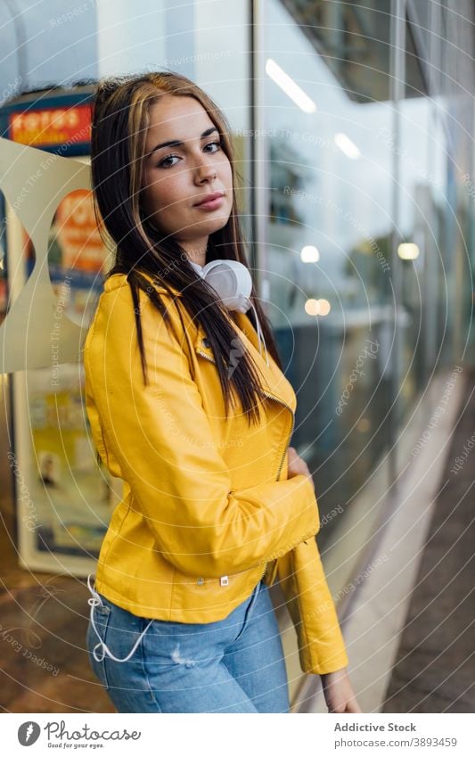 Junge Frau in gelber Jacke steht auf der Straße trendy Lederjacke Stil farbenfroh hell modern Windstille urban jung tausendjährig Lifestyle Glaswand Outfit