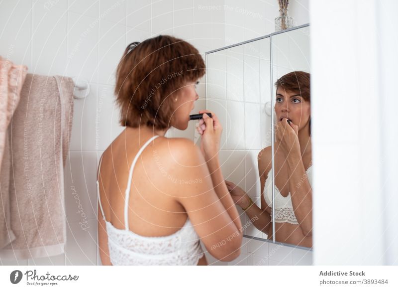 Frau trägt Lippenstift im Badezimmer auf Melisse bewerben Make-up heimwärts BH Gesicht täglich vorbereiten Kosmetik Schönheit Pflege verwöhnen jung Spiegel