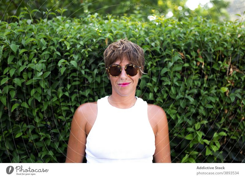 Stilvolle Frau mit Sonnenbrille lächelt in die Kamera Kurze Haare Erwachsener Park Sommer trendy Outfit Lächeln genießen grün Freude Glück sich[Akk] entspannen