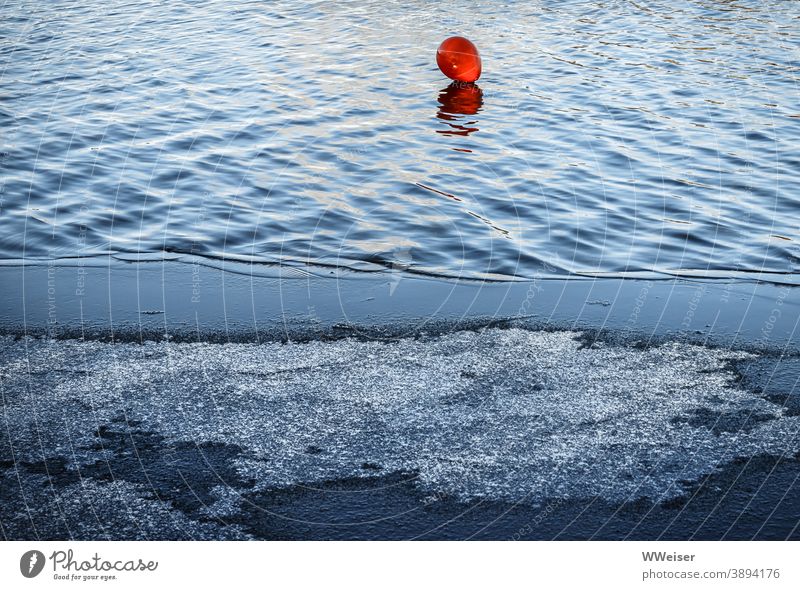 Der rote Luftballon hat sich aus dem Sommer auf das eisige Wasser verirrt See Eis kalt Winter Licht Wellen Muster gefroren frieren Kontrast warm-kalt Frost