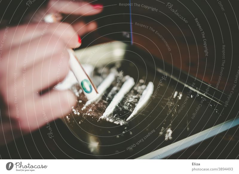 Eine Frau konsumiert eine weiße Line in pulverform mit einem gerollten Geldschein durch die Nase Drogenkonsum Koks weißes Pulver ziehen Linie Amphetamine Speed