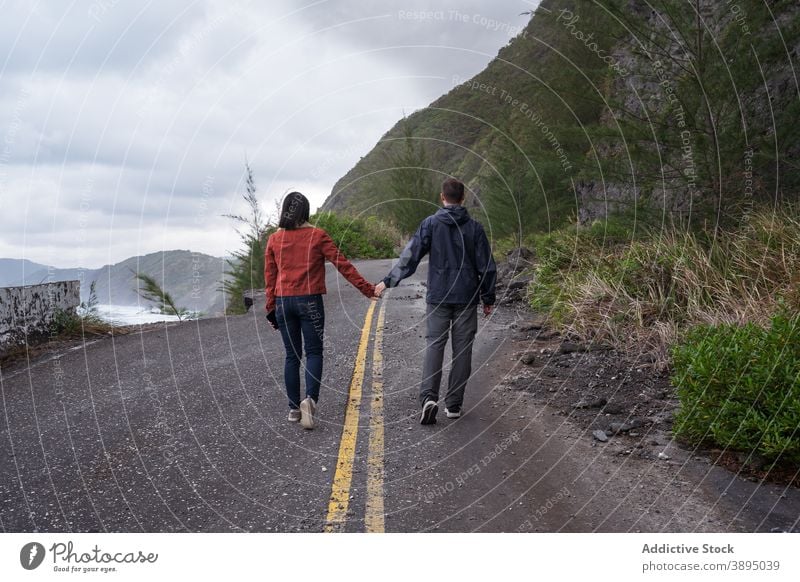 Anonymes Paar zu Fuß auf der Straße in der Nähe von Meer reisen MEER Küste stürmisch vernichten bedeckt Zusammensein Asphalt Küstenlinie Natur Ufer Spaziergang