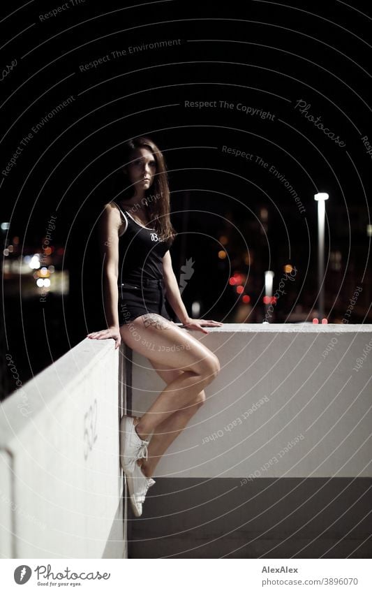 Portrait einer jungen Frau auf einer weißen Mauer vor Stadtlichtern in der Nacht junge Frau draussen Nachtleben Nachtstimmung nahe Nähe Kälte Licht Trägertop