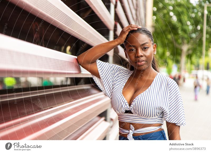Schwarze Frau in stilvoller Kleidung schaut in die Kamera auf der Straße Stil trendy Outfit modern urban Streifen jung Sommer Afroamerikaner schwarz ethnisch