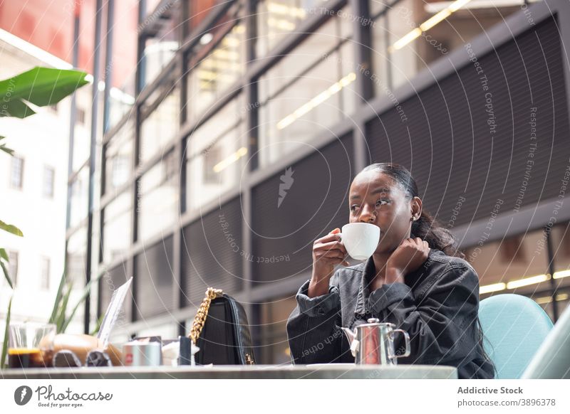Schwarze Frau genießt Wochenende im Café trinken Tee sich[Akk] entspannen genießen Getränk Kantine Inhalt ethnisch schwarz Afroamerikaner Tisch ruhen heiter