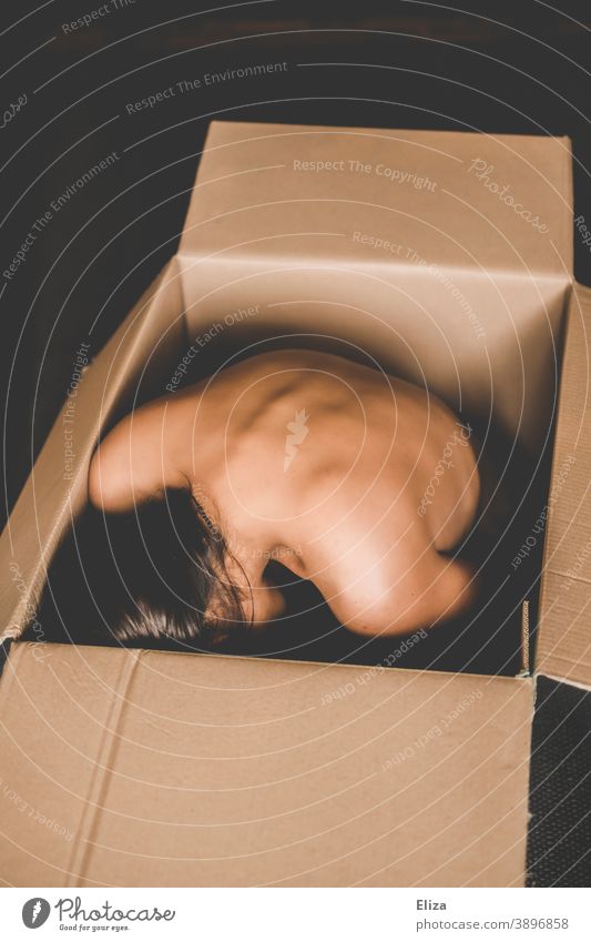 Eine nackte Frau zusammengekauert in einer Kiste Karton umzugskiste Versandkarton Menschenhandel Ware Mensch Paket schutzlos Verpackung ausgeliefert ungemütlich