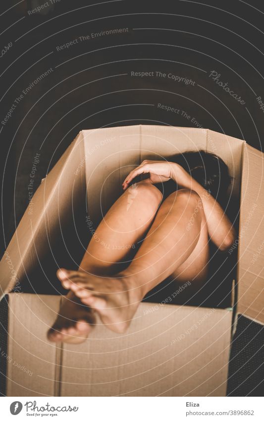 Eine nackte Frau zusammengekauert in einer Kiste Karton umzugskiste Versandkarton Menschenhandel Ware Mensch Paket schutzlos Verpackung ausgeliefert ungemütlich