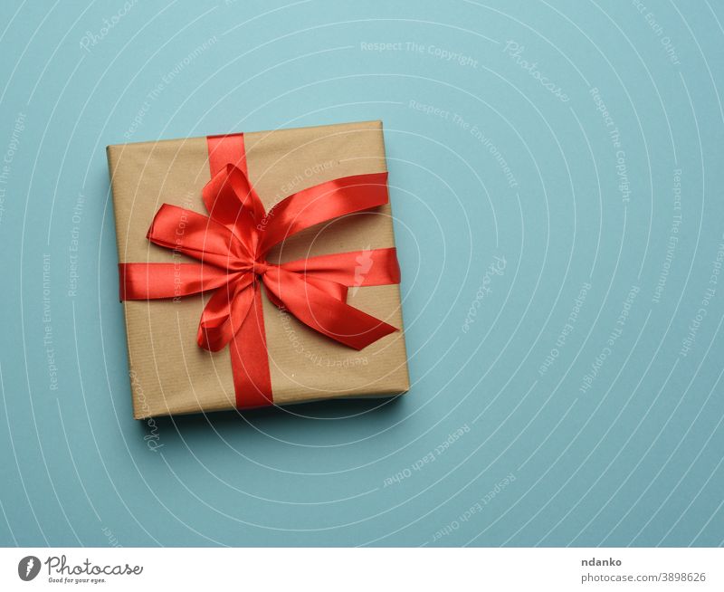 Schachtel mit braunem Papier umwickelt und mit einem roten Seidenband mit Schleife gebunden blau Kasten Geschenk Gruß Feiertag sehr wenige neu feiern Jahrestag