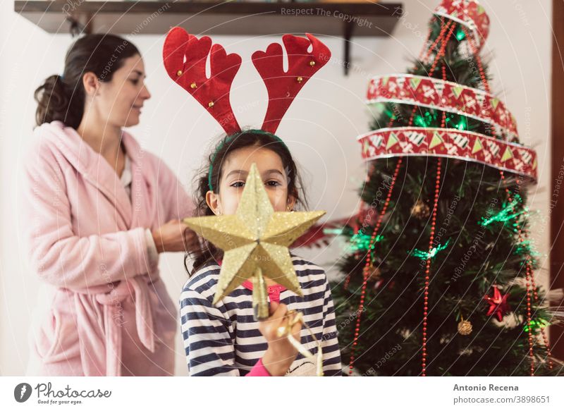 Mutter und Tochter im Bademantel und Pyjama platzieren Weihnachtsdekorationen in realistischer Szene Weihnachten Baum Kinder Platzierung Parteien Stern