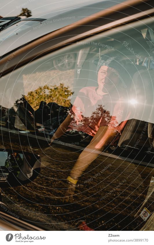 Junge Frau im Auto durch Scheibe fotografiert sommer sonne licht spiegelung autofahren mobilität fensterscheibe natur pkw fahrzeug lachen frau weiblich grün