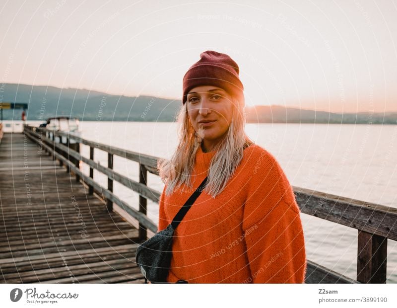 Junge Frau in der Abendsonne am Attersee attersee abendrot sonnenuntergang Natur Abenddämmerung Landschaft idylle österreich steg seeufer Außenaufnahme orange