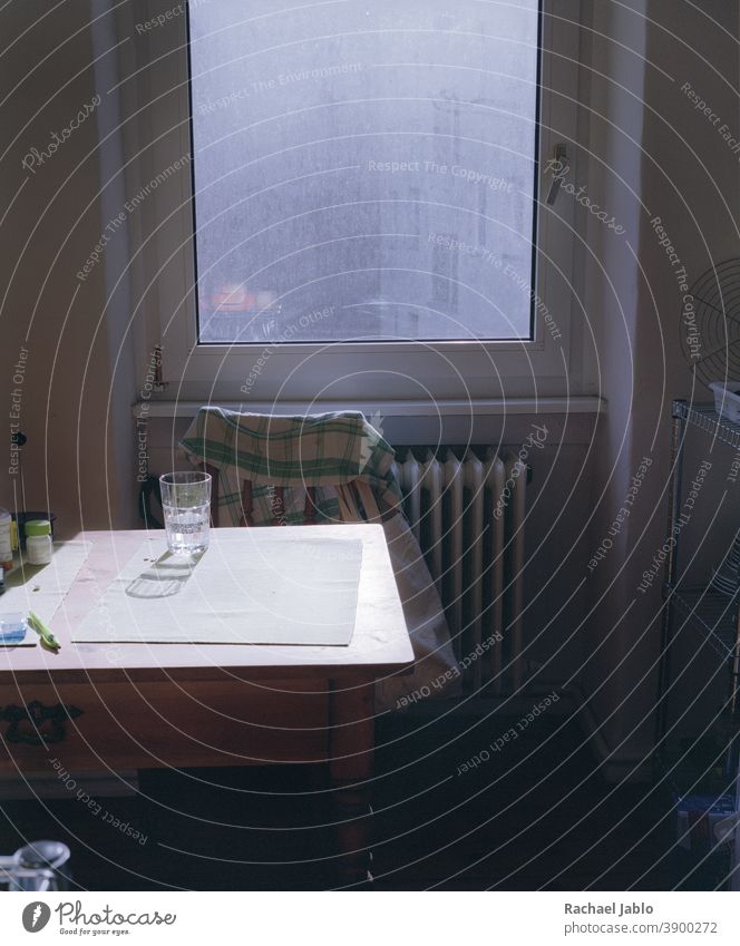 Glas auf dem Küchentisch vor einem schmutzigen Fenster Innenaufnahme Farbfoto Wohnung Licht Häusliches Leben Schatten ruhig Stuhl Holztisch