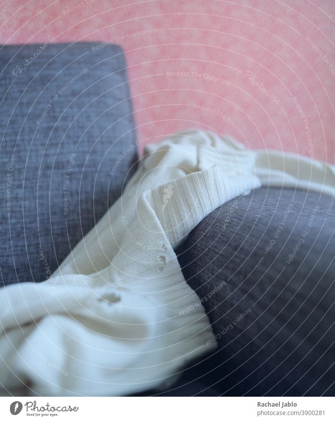 Motheatenweisser Pullover auf Sofa Motte Löcher rosa weiß rustikal Nahaufnahme Makro Stilleben