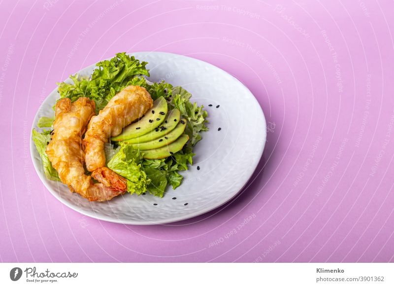 Avocado- und Riesengarnelensalat auf grünen Blättern. Festliches Abendessen. Gesunde Ernährung. Auf rosa Hintergrund. Salatbeilage Granele Suppengrün Vorteile