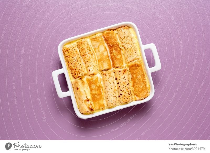 Mit Käse gefüllte und im Ofen gebackene Crêpes-Rolle, Ansicht von oben obere Ansicht Hintergrund blini Frühstück Auflaufform Komfortnahrung Essen zubereiten