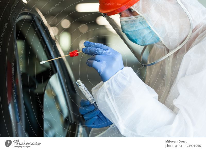 Medizinischer NHS-Mitarbeiter in persönlicher Schutzausrüstung beim Abstrich einer Person in einem Auto, der durch das mobile Testzentrum Coronavirus COVID-19 fährt,Verfahren zur Entnahme von Mund- und Nasenproben,Gesundheit und Sicherheit
