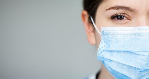 Nahaufnahme des Gesichts einer Ärztin des britischen NHS EMS, die eine blaue PSA-Schutzmaske trägt,COVID-19 Coronavirus-Krankheit,globaler Ausbruch einer Pandemie,tödliche SARS-CoV-2-Epidemie,Kopierfeld auf der linken Seite des Rahmens