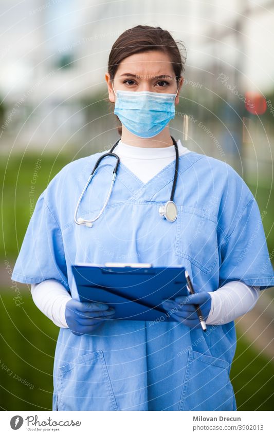 Porträt einer sehr müden und erschöpften Ärztin des britischen NHS vor einem Krankenhaus, verschwommener, unscharfer Hintergrund, Coronavirus-COVID-19-Pandemie-Ausbruchskrise, überlastetes medizinisches Personal in langen Schichten