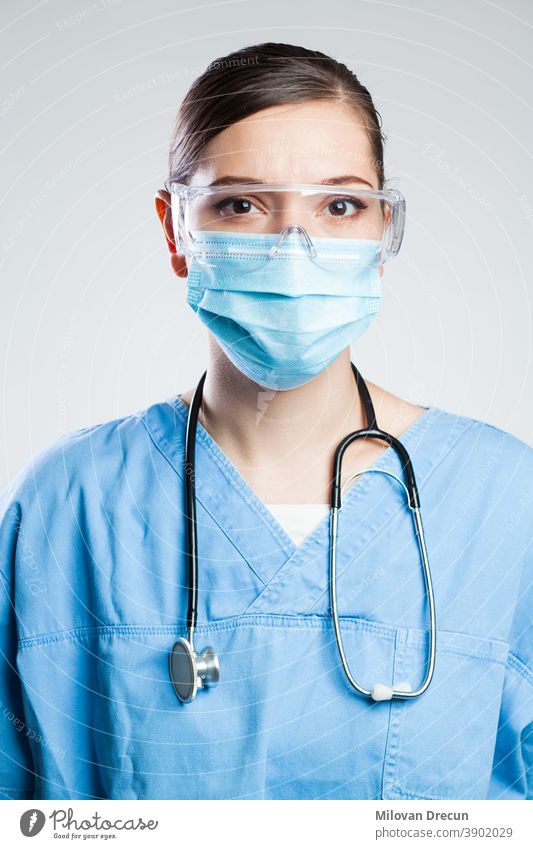 Junge seriöse Ärztin eines britischen EMS-Schlüsselarbeiters, Porträt isoliert auf weissem Hintergrund in einer Intensivstation, mit persönlicher Schutzausrüstung (PSA), Gesichtsmaske, Schutzbrille, COVID-19-Pandemie-Ausbruchskrise
