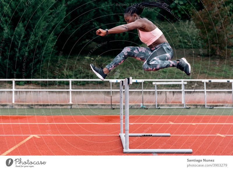 Afrikanisch-amerikanischer Athlet Sprinter springt über eine Hürde entschlossen muskulös springen Afro-Look Amerikaner Beginn Ehrgeiz Motivation Bewegung