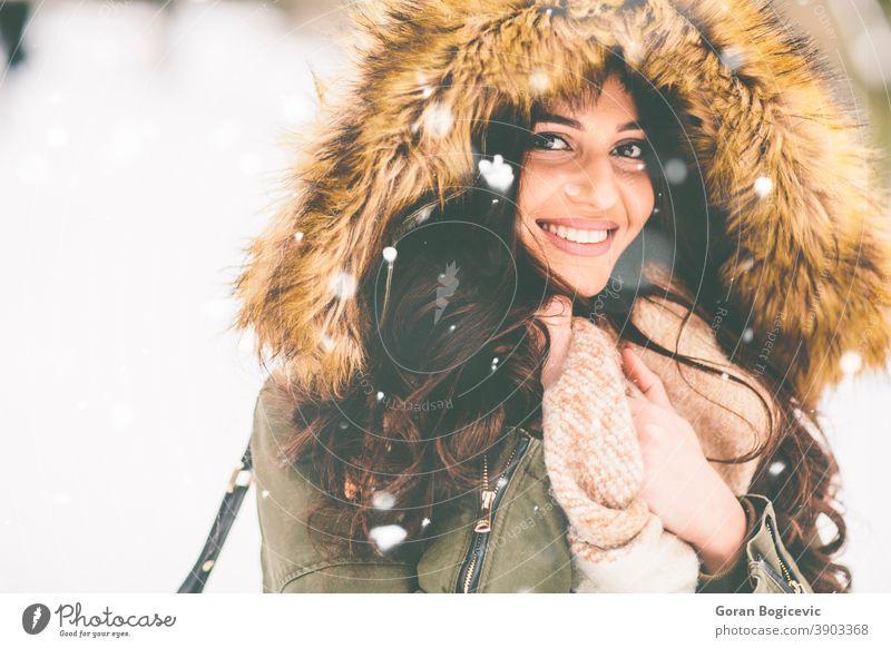 Junge Frau mit Pelzkapuze im Park auf dem Schnee schön Nahaufnahme Kleidung Mantel kalt Mode Fell Mädchen Glück Kapuze Jacke Natur im Freien Porträt hübsch