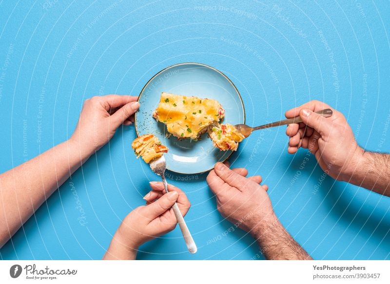 Vegetarische Lasagnenscheibe, Ansicht von oben. Menschen, die ein Stück Lasagne essen obere Ansicht Backwaren Béchamelsauce Blauer Hintergrund Kohlenhydrate