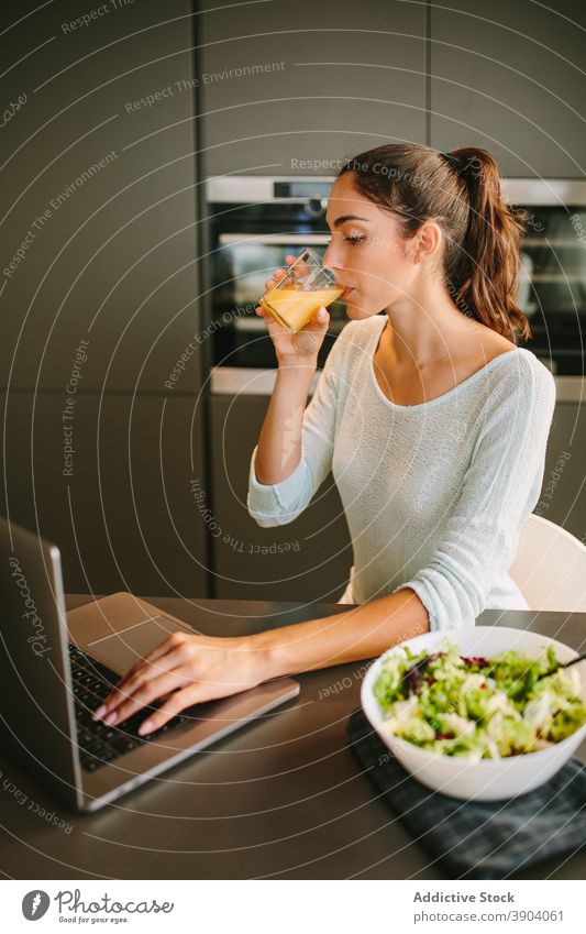 Frau trinkt Saft und arbeitet am Laptop in der Küche trinken freiberuflich orange Mittagessen heimwärts abgelegen Unternehmer Projekt Getränk frisch Erfrischung