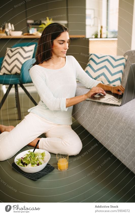 Junge Frau isst Salat und arbeitet am Laptop Arbeit essen zu Hause Salatbeilage Gesundheit jung Apparatur Lebensmittel lässig Lifestyle Internet online