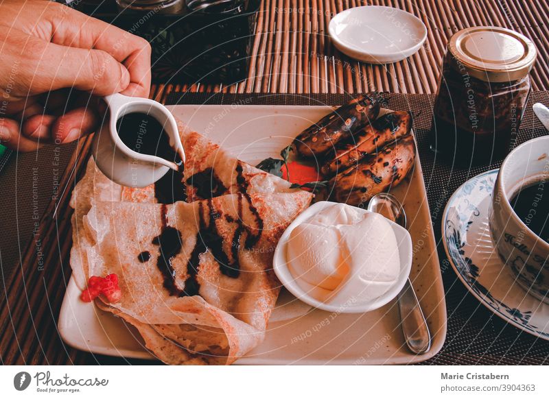 Gegrillte Banane, Pfannkuchen und Kokosnusseis, selbst gekochtes veganes Frühstück, um gesund zu bleiben und die Hausquarantäne wegen der Covid-19-Pandemie zu bewältigen