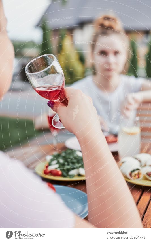 Frau trinkt im Sommer Rotwein beim Abendessen im Freien in einem Hausgarten heimwärts Festessen habend Picknick Lebensmittel Mann Zusammensein Barbecue Tisch