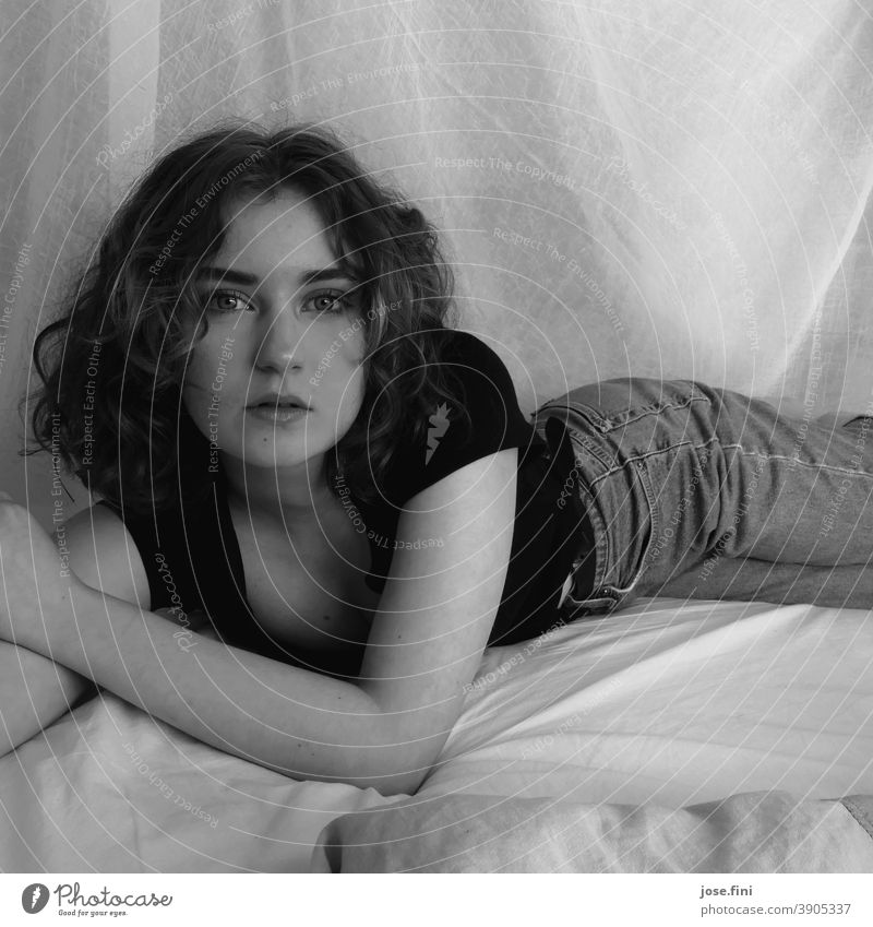 Portrait einer jungen Frau, liegend, mit Blick in die Kamera, in schwarz-weiß. träumen Bett ästhetisch Selbstvertrauen natürlich authentisch frisch schön