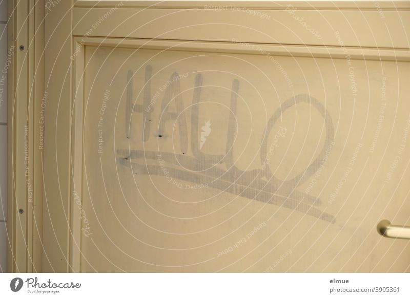 an eine beigefarbene Holztür hat jemand "HALLO" geschrieben und doppelt unterstrichen / Schmiererei / Kontaktsuche Hallo Tür Wort Jugendkultur Netzjargon