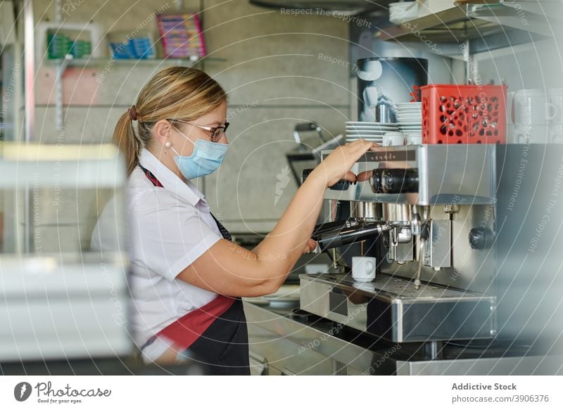 Barkeeper in medizinischer Maske bereitet Kaffee zu vorbereiten Coronavirus COVID Mundschutz verhindern behüten Pandemie Maschine Frau Barista Espresso Kantine