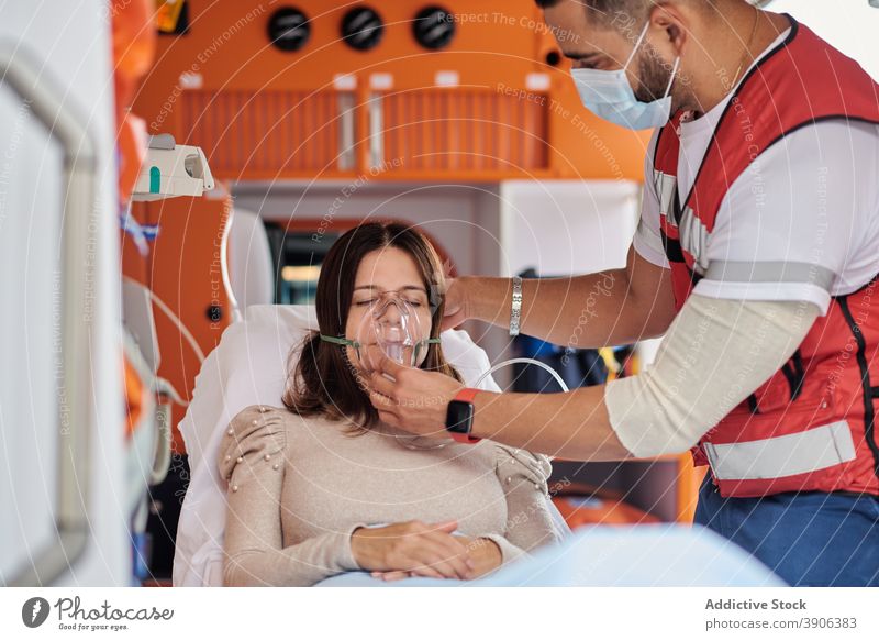 Sanitäter behandelt Patient im Rettungswagen Krankenwagen PKW Notfall Puls Oximeter Beatmungsgerät Mundschutz geduldig medizinisch Trage Medizin Gesundheit