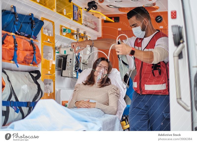 Sanitäter behandelt Patient im Rettungswagen Krankenwagen PKW Notfall Puls Oximeter Beatmungsgerät Mundschutz geduldig medizinisch Trage Medizin Gesundheit