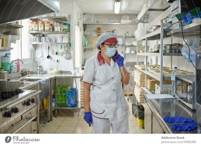 Krankenhaus Koch sprechen am Telefon in der Küche Coronavirus Mundschutz behüten reden Smartphone Arbeit Frau Pandemie Bund 19 COVID19 Seuche Job professionell
