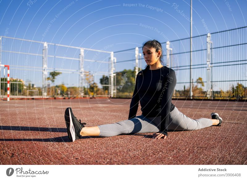 Flexible Frau macht Spagat auf Sportplatz Split Übung beweglich Dehnung Bein calisthenics Training Sportlerin schlanke Wohlbefinden üben passen Athlet