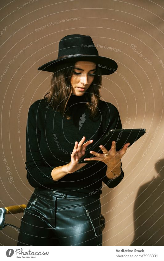 Frau in stilvollen schwarzen Outfit mit Tablette in der Nähe von Fahrrad benutzend Stil trendy Apparatur Gerät prüfen Reisender Hipster Lifestyle modern Browsen