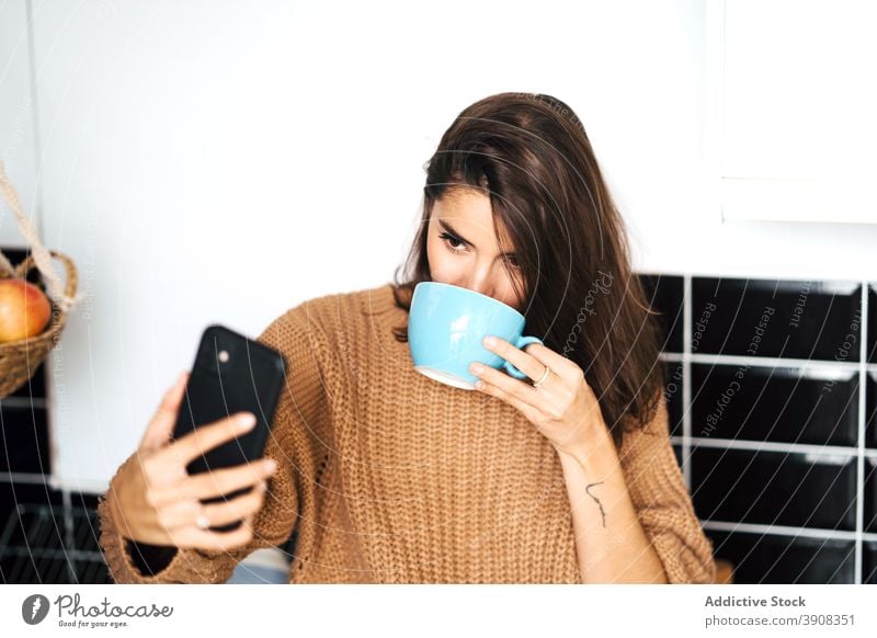 Frau trinkt Kaffee nimmt Selfie mit Smartphone Browsen heimwärts Selbstportrait Küche sich[Akk] entspannen Tasse Wochenende Foto heimisch Bild