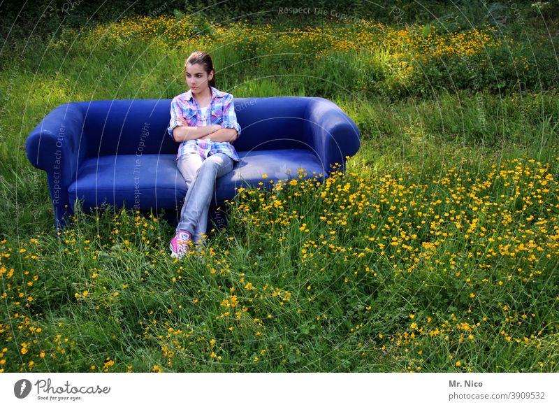 Junges Mädchen sitzt auf einem blauen Sofa welches auf einer Wiese steht sitzen Ruhe entspannend entspannt Porträt Glück warten Gras Natur Umwelt natürlich